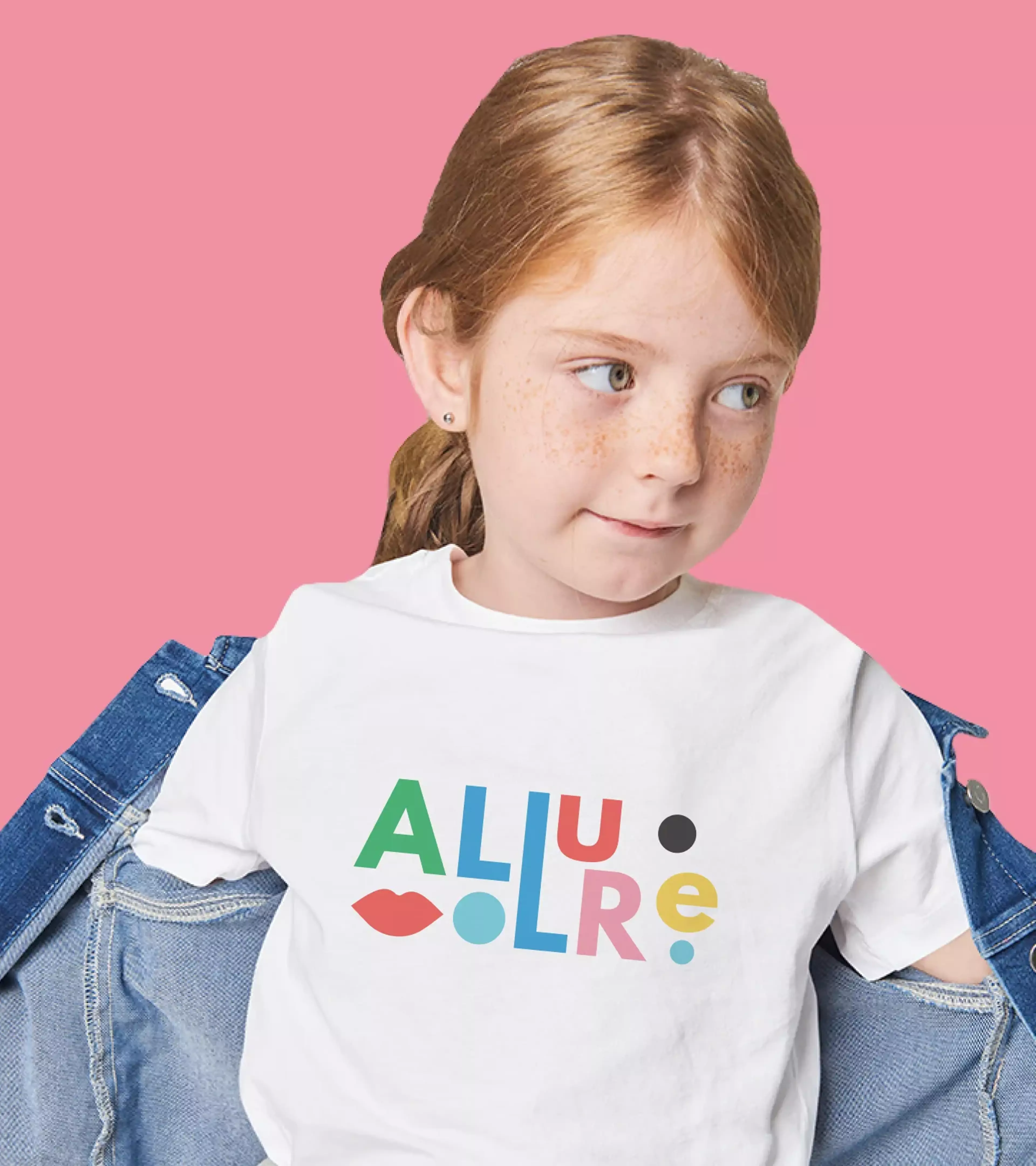 A young girl with red hair wearing a shirt with the design of Allure on a pink background