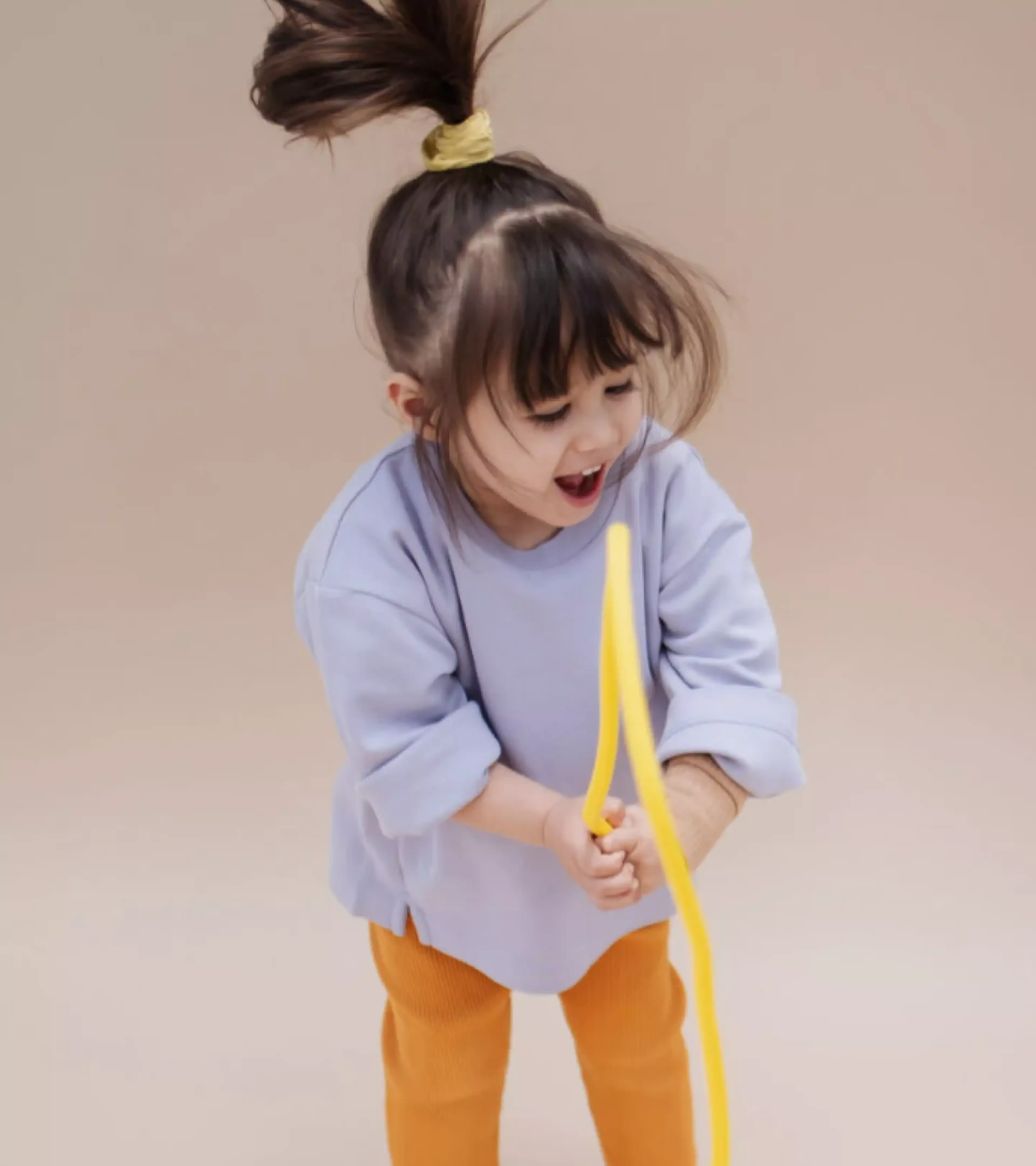 An image of a jumping young girl playing with a yellow rope