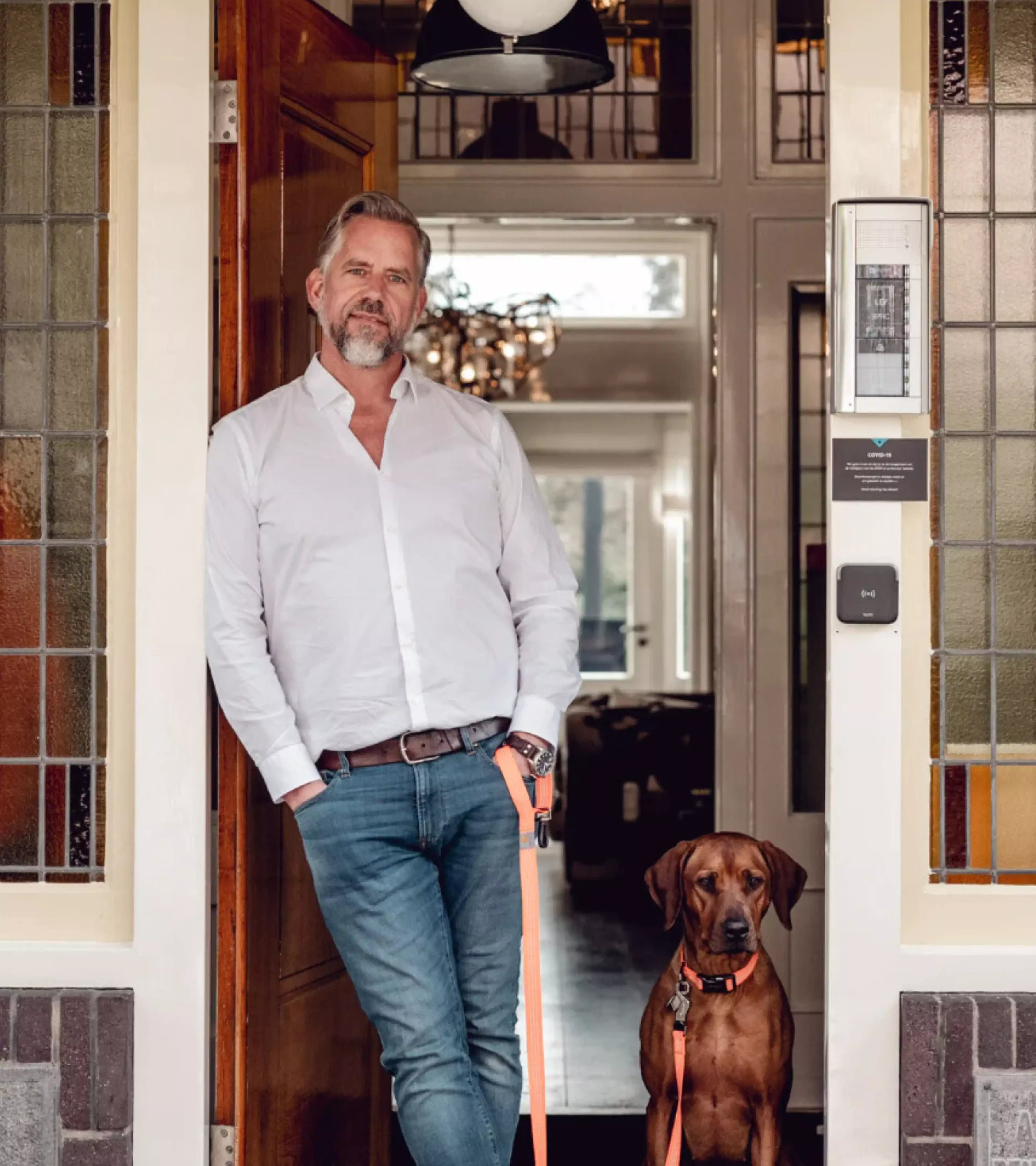 A photo of the owner of the brand with his dog standing in the opening of a house