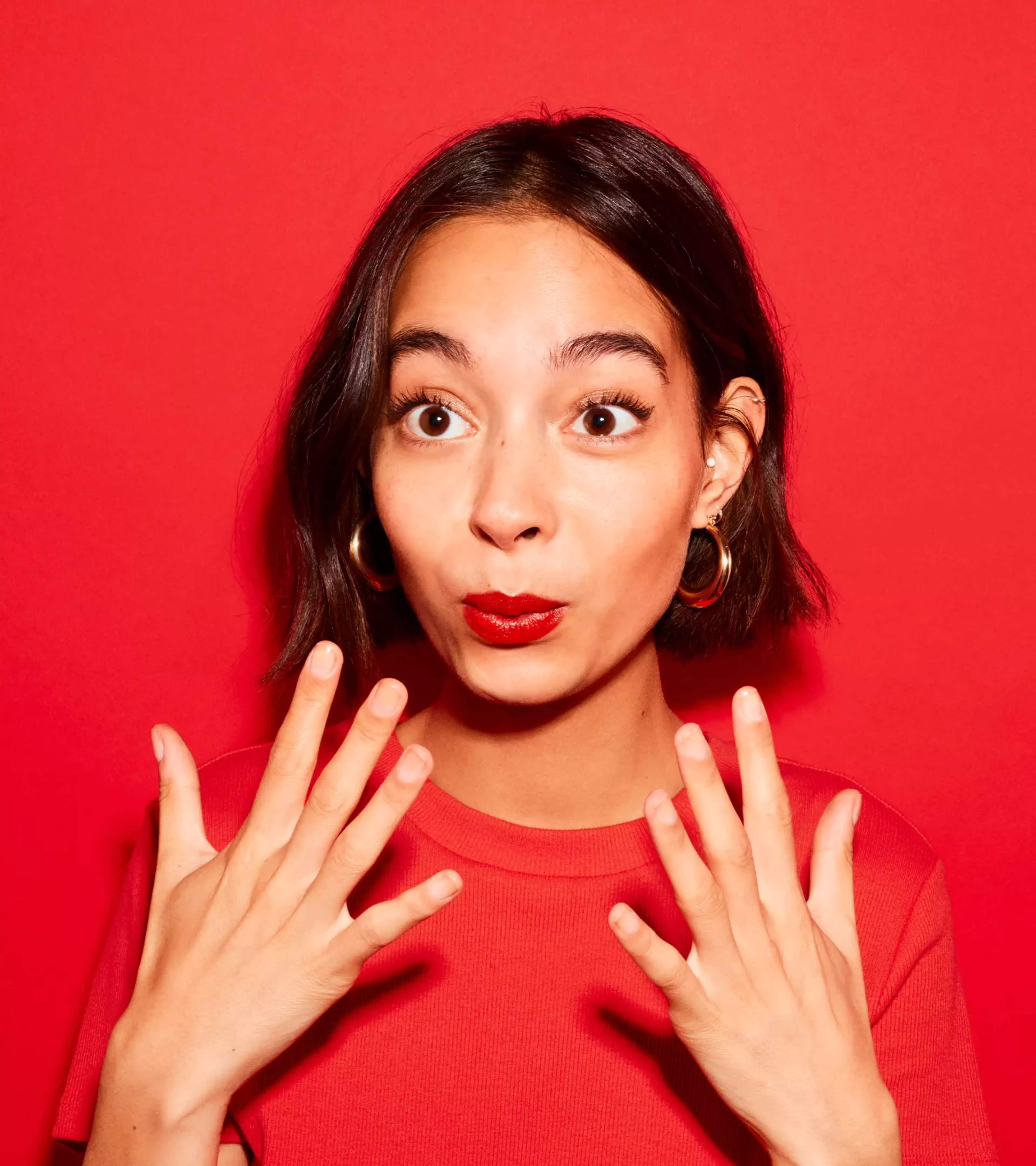 An image of a woman holding her hands to her mouth on a red background