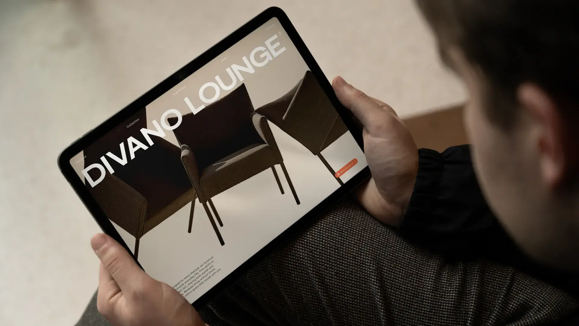 Person holding a tablet displaying an advertisement for "Divano Lounge" seating with images of two modern chairs on the screen.