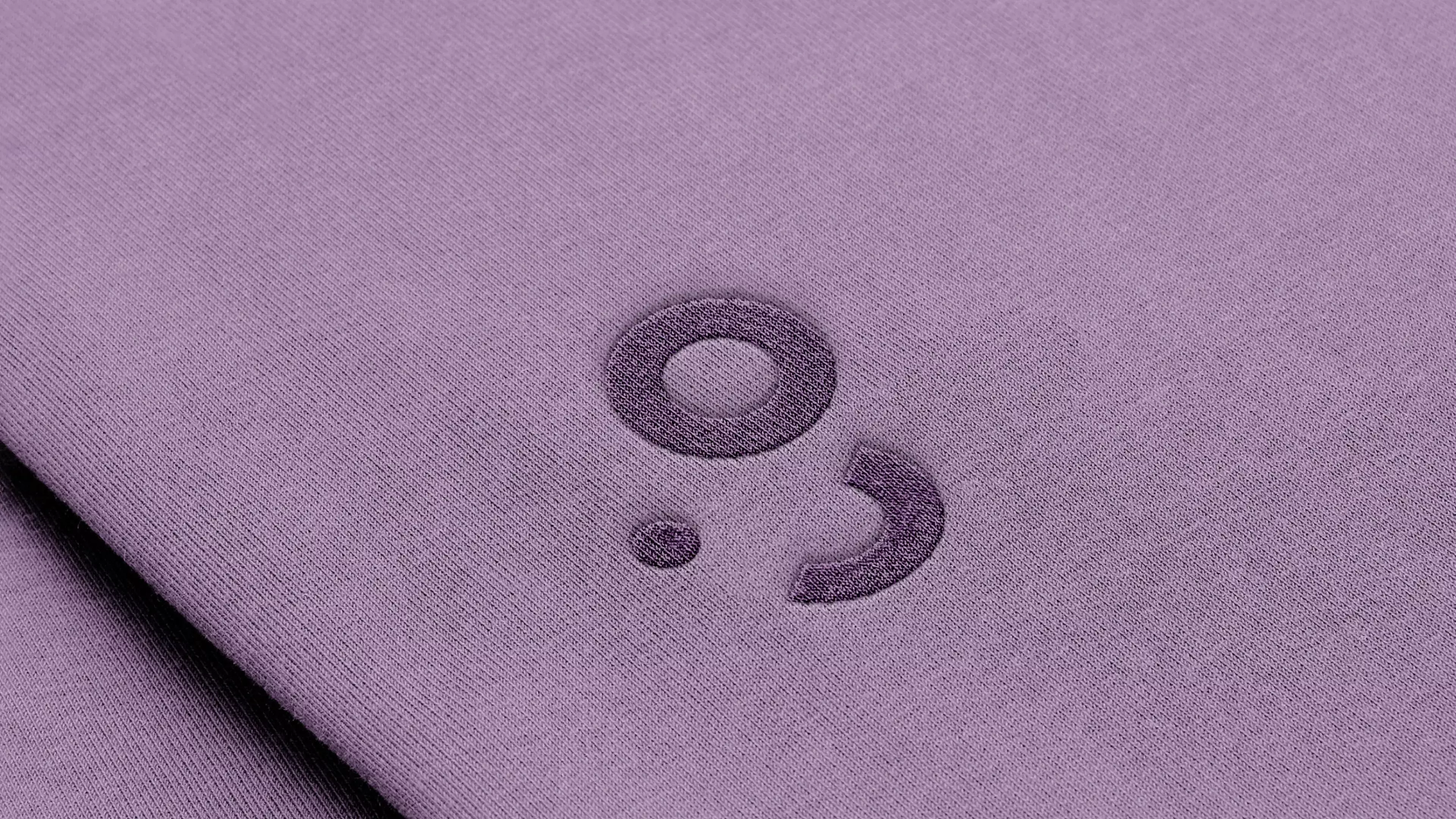 A logomark printed on a purple sweater