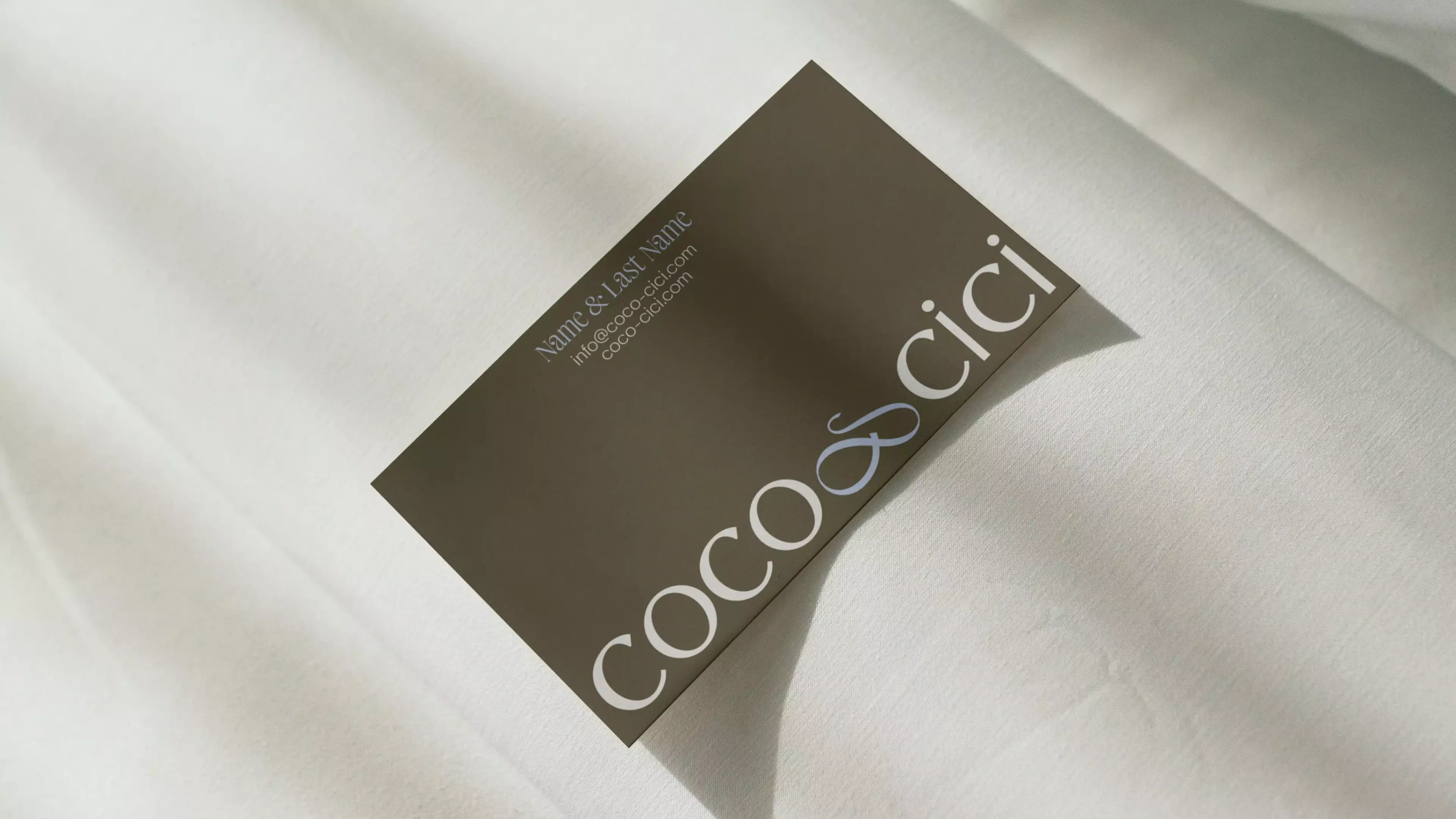 Beige textile in the back with the business card of Coco & Cici on top.